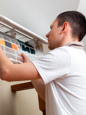 Male technician cleaning air conditioner indoors